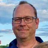 Martin, med glasögon och blårutig skjorta, framför en kvällshimmel.